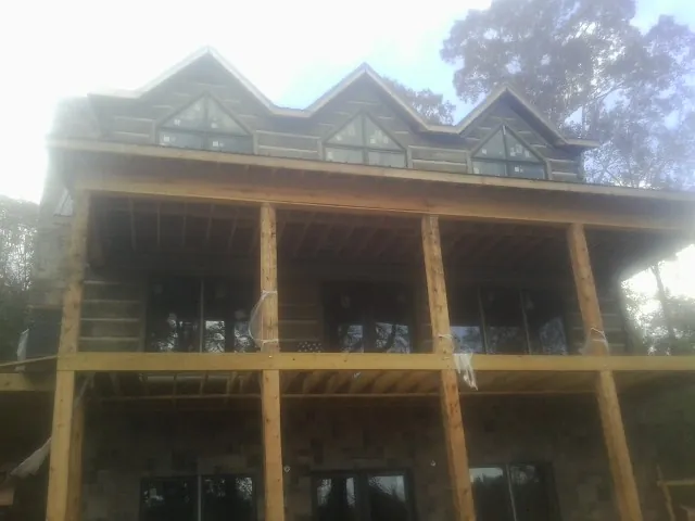 Dormers and porch framing on a large log home under construction — Roof Coating work by our crew in Youngsville