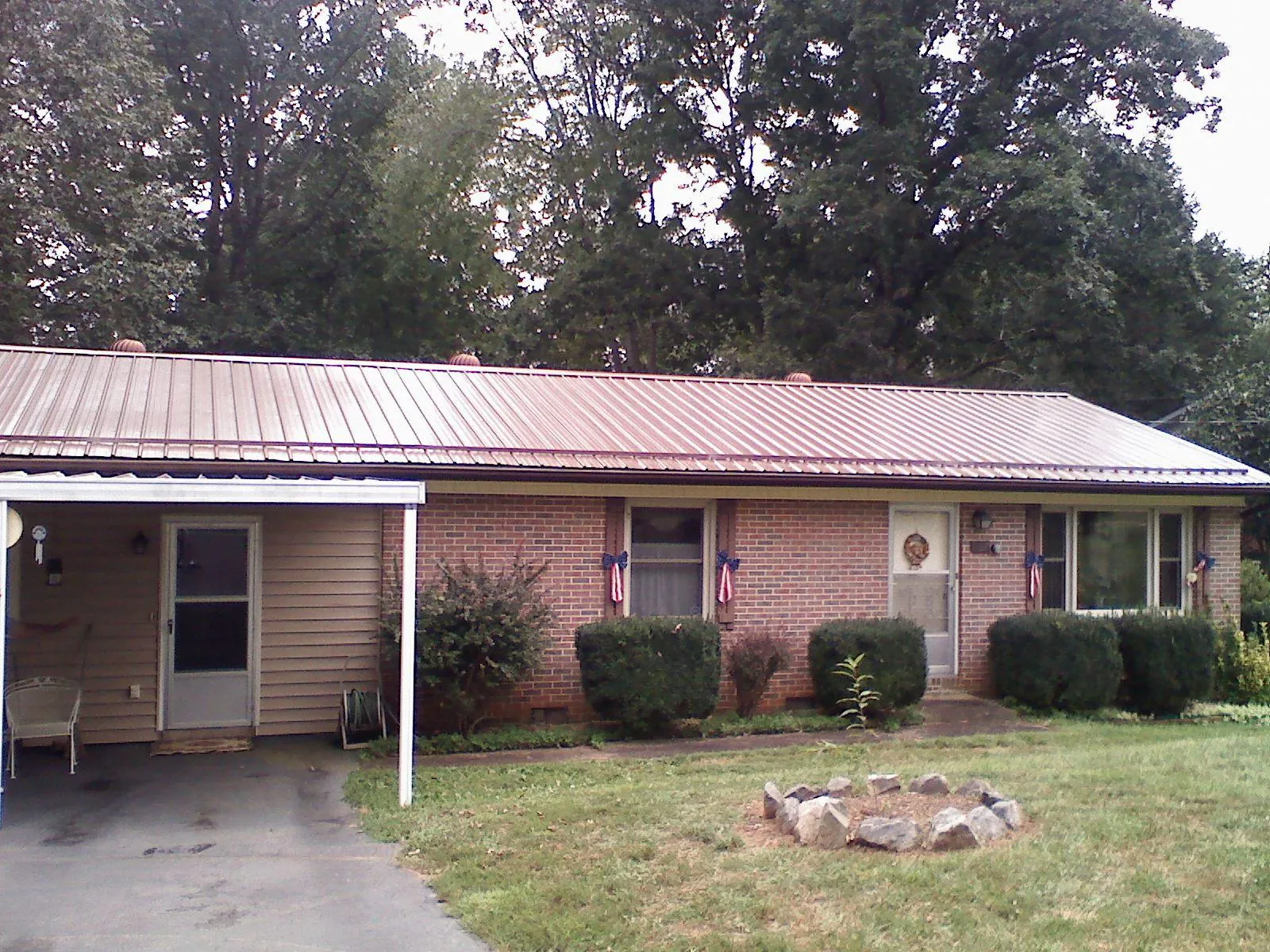 Bronze metal roof and carport on a brick ranch home — Roof Repair work by our crew in Youngsville